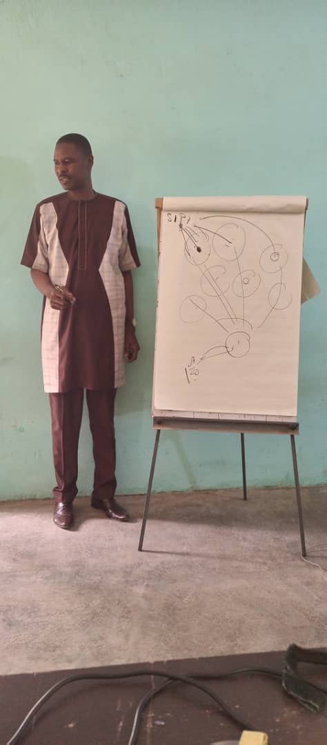 Dr Ismaïla IMOROU ISSA beside a diagram drawn on a flip chart